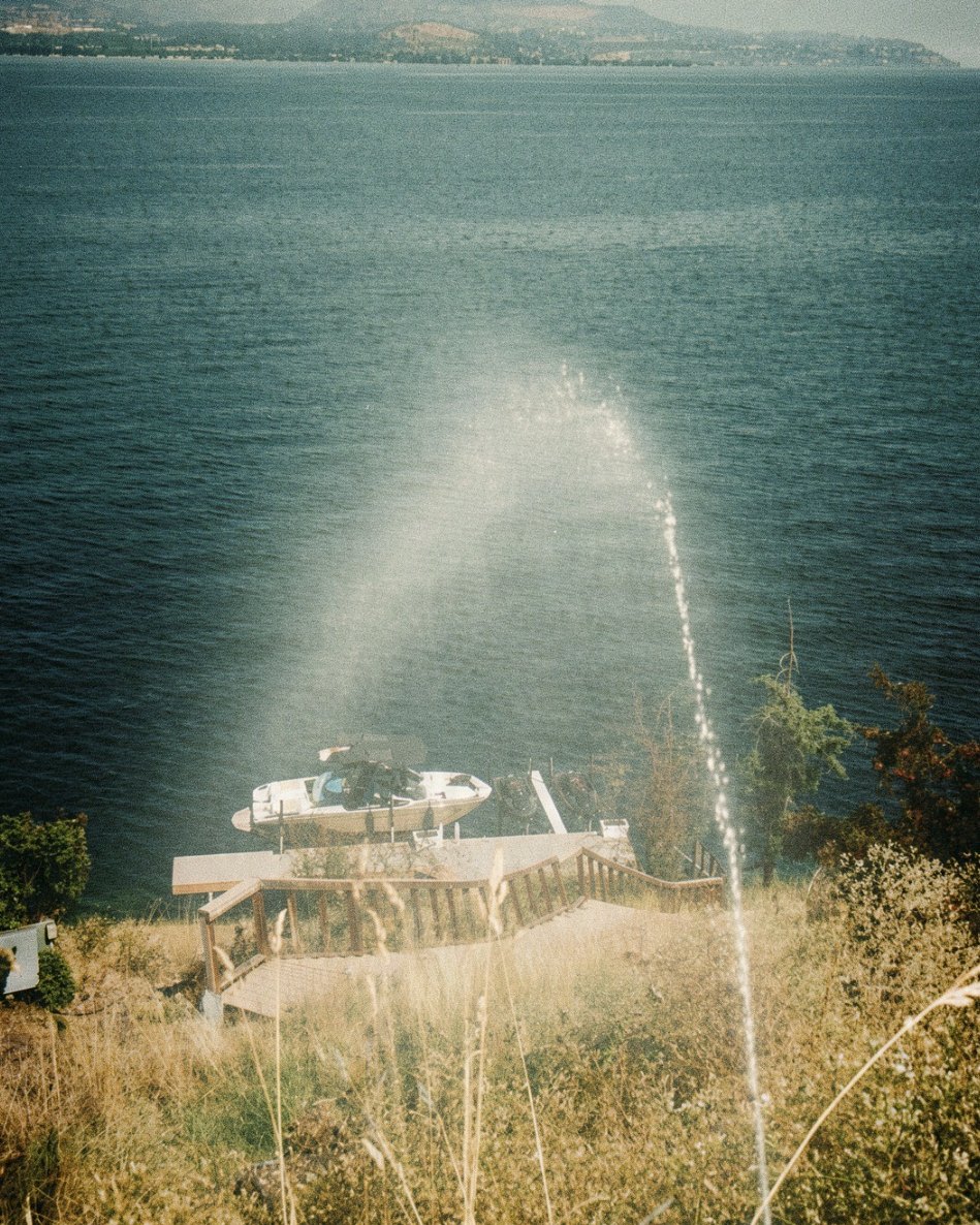 Lakeside wildfire sprinkler spraying over a dock and boat on Okanagan Lake